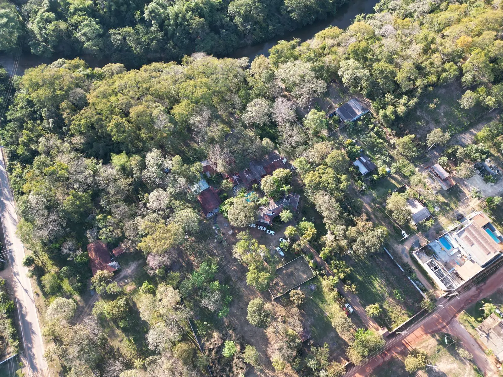 Vista aérea da Chácara Namastê entre as árvores, próxima ao rio