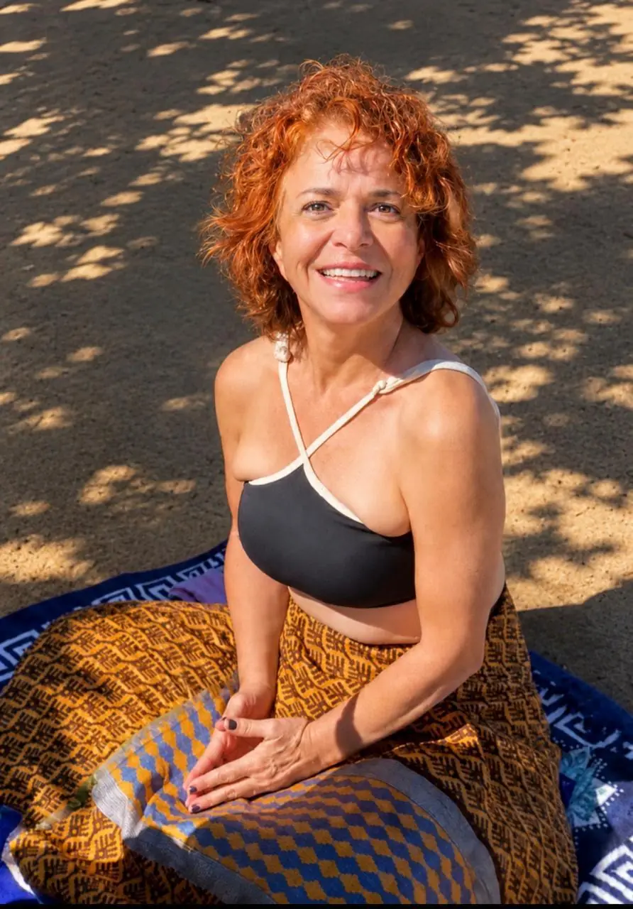 Sita Madhu sentada e sorrindo, em momento contemplativo ao ar livre